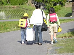 Two sisters wearing pink randoseru. One of them with a yellow plastic cover worn by 1st graders.