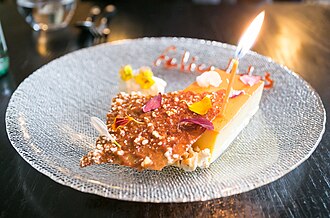 A slice of flan accompanied with a birthday candle.