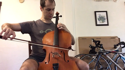 A man playing a tenor violin of the Violin octet family, in a sitting position.
