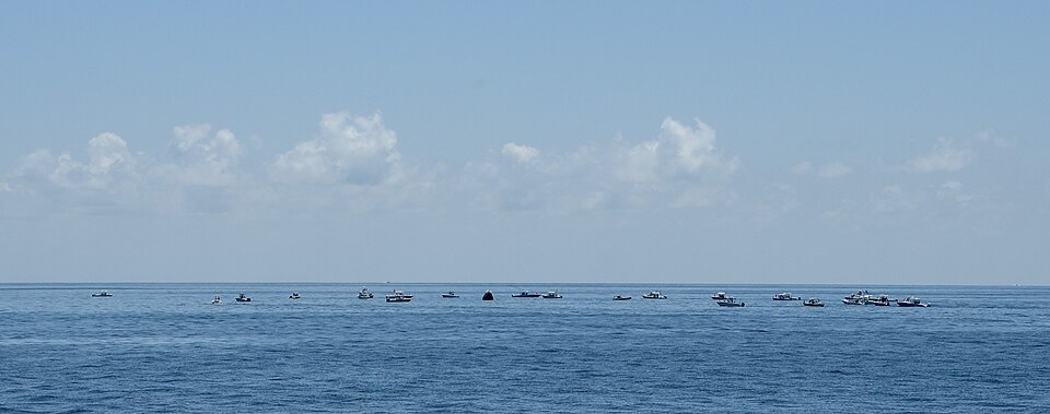 Large numbers of private boats create a circle around the Endeavour capsule.