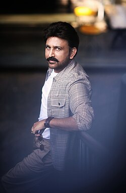 Ramesh looking towards his left and smiling, wearing a coat