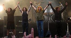A four-piece band cheering the audience at the end of a concert