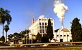 Photo of shorter building with smoke coming out of smokestack next to five-story office building