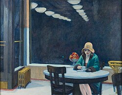 A woman sits alone at a table with a coffee cup in a brightly lit automat