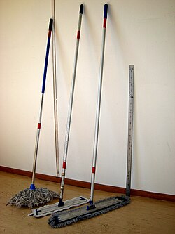 Three mops leaning against a wall