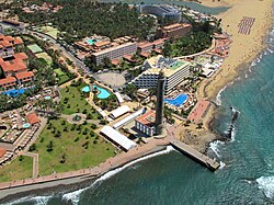 Aerial view of Faro de Maspalomas showing a cluster of hotel complexes, the lighthouse, beaches and sea