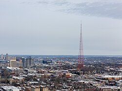 Red TV tower with downtown Kansas City, Missouri in the background, as seen from a drone.
