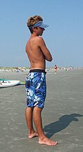 A man at the beach wearing boardshorts