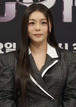 Ailee wearing a gray blazer and posing for the camera during Veiled Cup' production conference in 2026