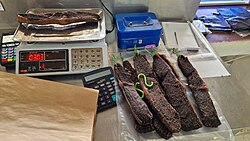 Several strips of dried biltong being weighed on a digital scale and packaged on a counter