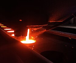 In-stream inoculation addition while molten cast iron is poured to a green sand mold in a foundry