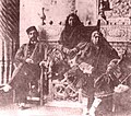 Queen mother Malek Jahan Khanom sitting on the steps of the throne. Naser al-Din Shah (left) and Princess Ezzat ed-Dowleh (right) sit on chairs beside her. Pre 1873.