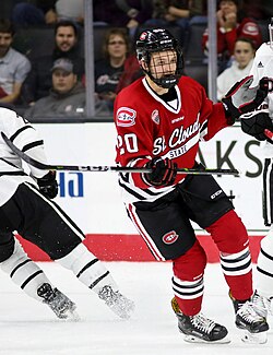 Ice hockey player in a red jersey skating while holding his stick out