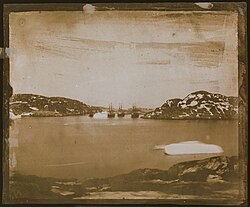 a sepia toned photographic view of four ships in the distance sailing through a channel.