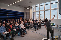 Picture of developer Eric "ConcernedApe" Barone at Hackfort 2019, describing the development of Stardew Valley to a crowd