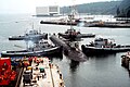 Naval Submarine Base Bangor with tug Mishawaka (rear left) and three other Natick-class tugs guiding the USS Ohio (SSGN-726) out of dry dock at Delta Pier