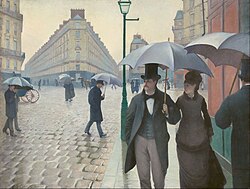 Oil painting depicting a street scene. The viewer is on a sidewalk. A couple formed by a white man in a green tailcoat, black top hat, green vest and gray trousers holding an umbrella and a white woman in a black hat and brown long dress holding the man's arm walk towards the viewer. The cobbled road is wet and the sky has yellowish color. Across the street, a 5-storey building with an acute corner towards the viewer. There at least 5 figures or groups in long clothes holding open umbrellas.