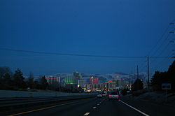 Dusk view of a freeway descending into a neon lit cityscape