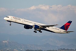 A white and blue 757 takes off with the Hollywood sign in the background