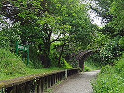 The Camel Trail passing through the disused partially-restored Dunmere Halt, under a bridge that carries road traffic through the hamlet