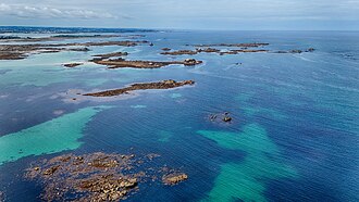 Aerial photograph showing shallow turquoise waters and scattered rocky islets near Roscoff on the Brittany coast of France.