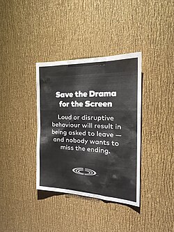 A paper poster on the wall that reads: "Save the drama for the screen: Loud or disruptive behaviour will result in being asked to leave — and nobody wants to miss the ending."