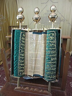 A torah adorned in green felt and gold