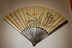 A hand fan with a flower motif and a poem painted on its surface