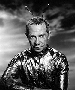 A black-and-white photo of Walston as a Martian, with a shiny suit and antenna on his head