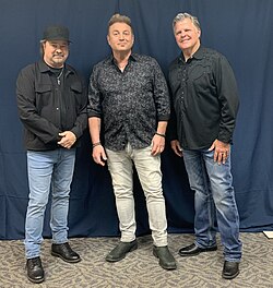 The three members of the Frontmen against a blue background