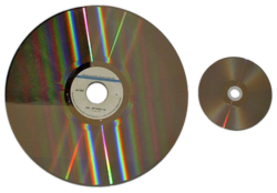 Photograph of two optical disc next to each other. The left disc's diameter is more than twice as large as the right disc's.