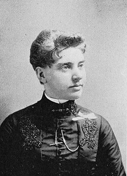 19th-century B&W portrait photo of a woman with her hair in an up-do, wearing a dark, fitted blouse.