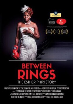 Against a dark background, Esther Phiri stands facing the camera. She is wearing a white formal strapless dress, a white hat with lace decoration, and a pearl necklace - reminiscent of bridal wear, and on her right hand is a red boxing glove.
