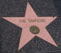 A red star with a small medal inside of it and text that reads THE SIMPSONS.