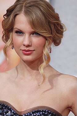 Taylor Swift wearing a dark strapless dress with her hair pinned up