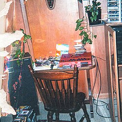 A photograph, taken by J. Cole himself when he was fifteen years old, of his first home studio; a sampler and several other items lay on a table while his mother's CD collection is strewn about the room