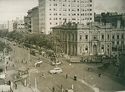 Electric trams and motor cars at a crossroads in a densely built up area