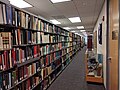 A shelf of books extends from the left to right along a carpeted hallway.