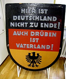Black, red and gold West German sign reading "Hier ist Deutschland nicht zu Ende. Auch drüben ist Vaterland!"