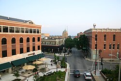 A photograph of a downtown four-way intersection with one office building each visible on three of the corners, surrounded by sunshades, greenery, traffic lights, and a few cars