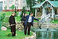 George Bush and Vladimir Putin fish from a fish pond, while an aide holds a landing net