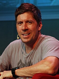 A headshot of a man with a headset smiling.