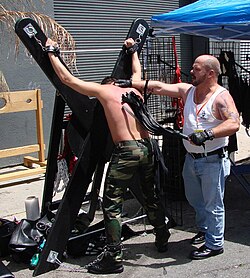 A man is flogged with a multi-tailed whip as he is tied to an X-cross