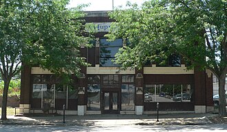 Two-story brick building with stone trim, "Hupmobile" inscribed near top center