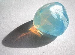 Tyndall effect in an opalite: it scatters blue light making it appear blue from the side, but orange light shines through. Opal is a gel in which water is dispersed in silica crystals.