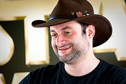 A headshot of a man in a cowboy hat smiling. The Star Wars logo is partially visible in the background.