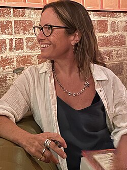 author sitting on couch holding a book and pen