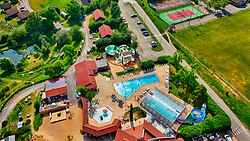 Aerial photo of an outdoor swimming pool complex with slides, buildings, and landscaped surroundings.