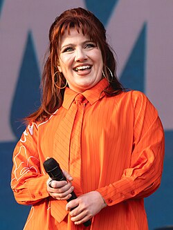 CMAT onstage at Wide Awake 2025, wearing an orange shirt and a tie