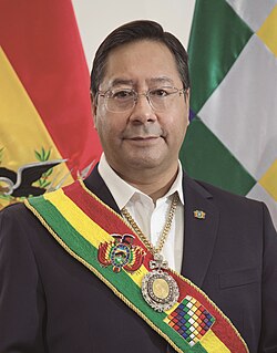 Luis Arce in the Casa Grande del Pueblo, invested with the symbols of command. Behind are the dual flags of Bolivia: the national flag and the Wiphala.
